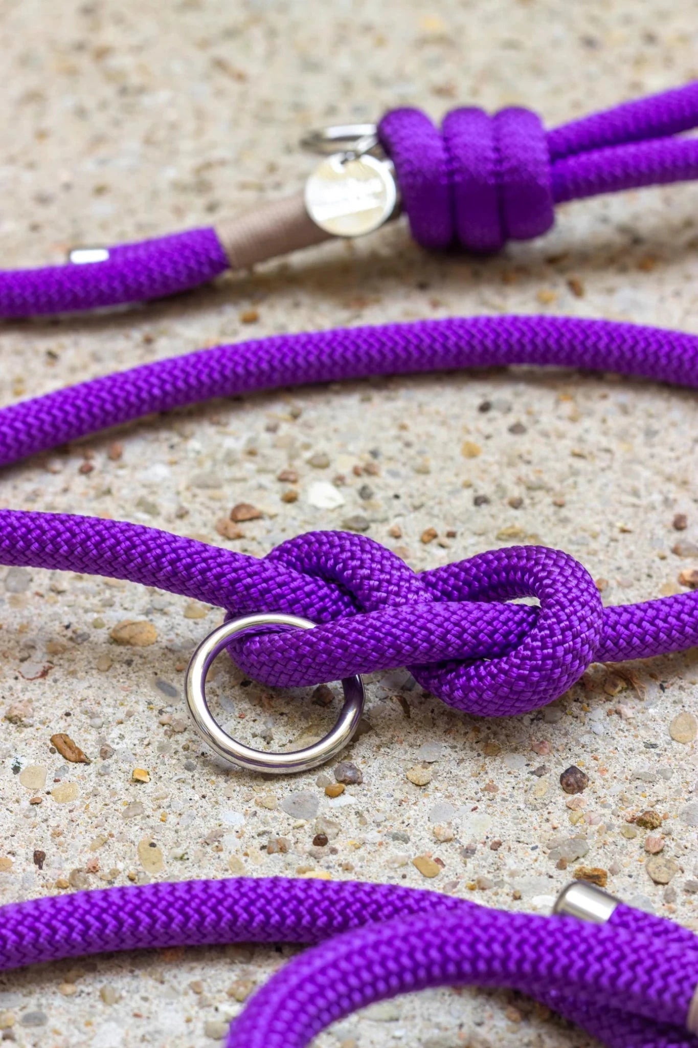 Close-up of purple rope with metal loops on a textured surface