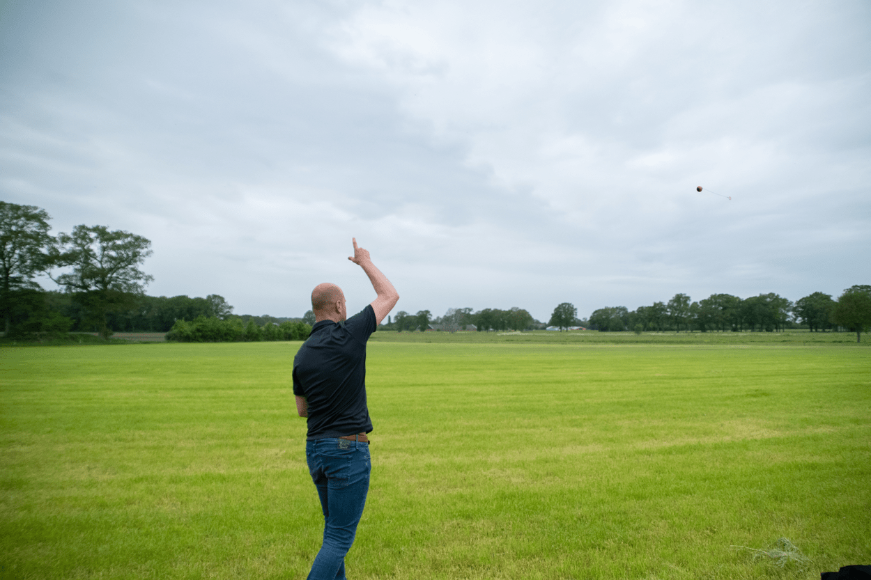 Man throwing a frisbee in a grassy field on a cloudy day