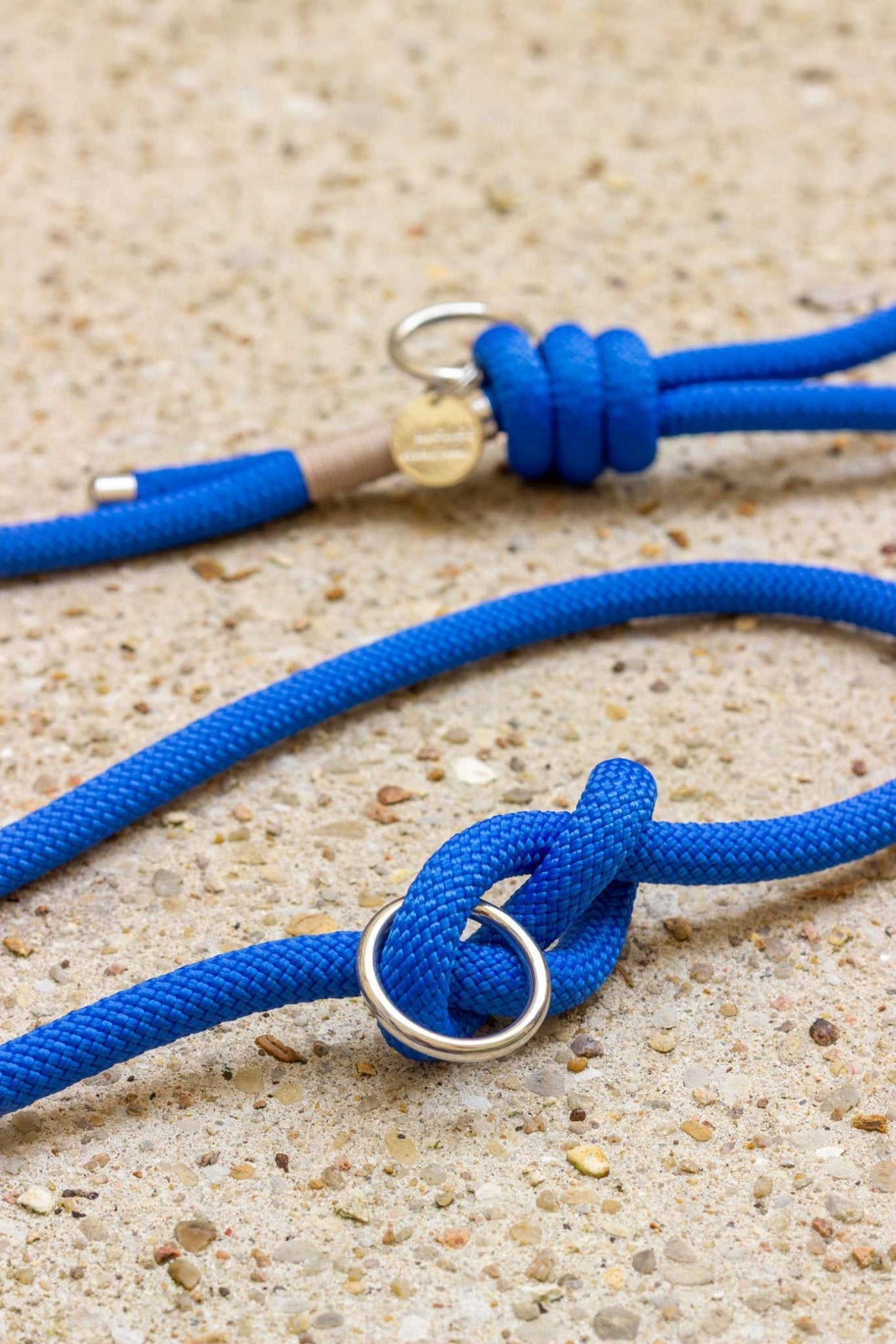 Blue rope with metal loops on a sandy surface