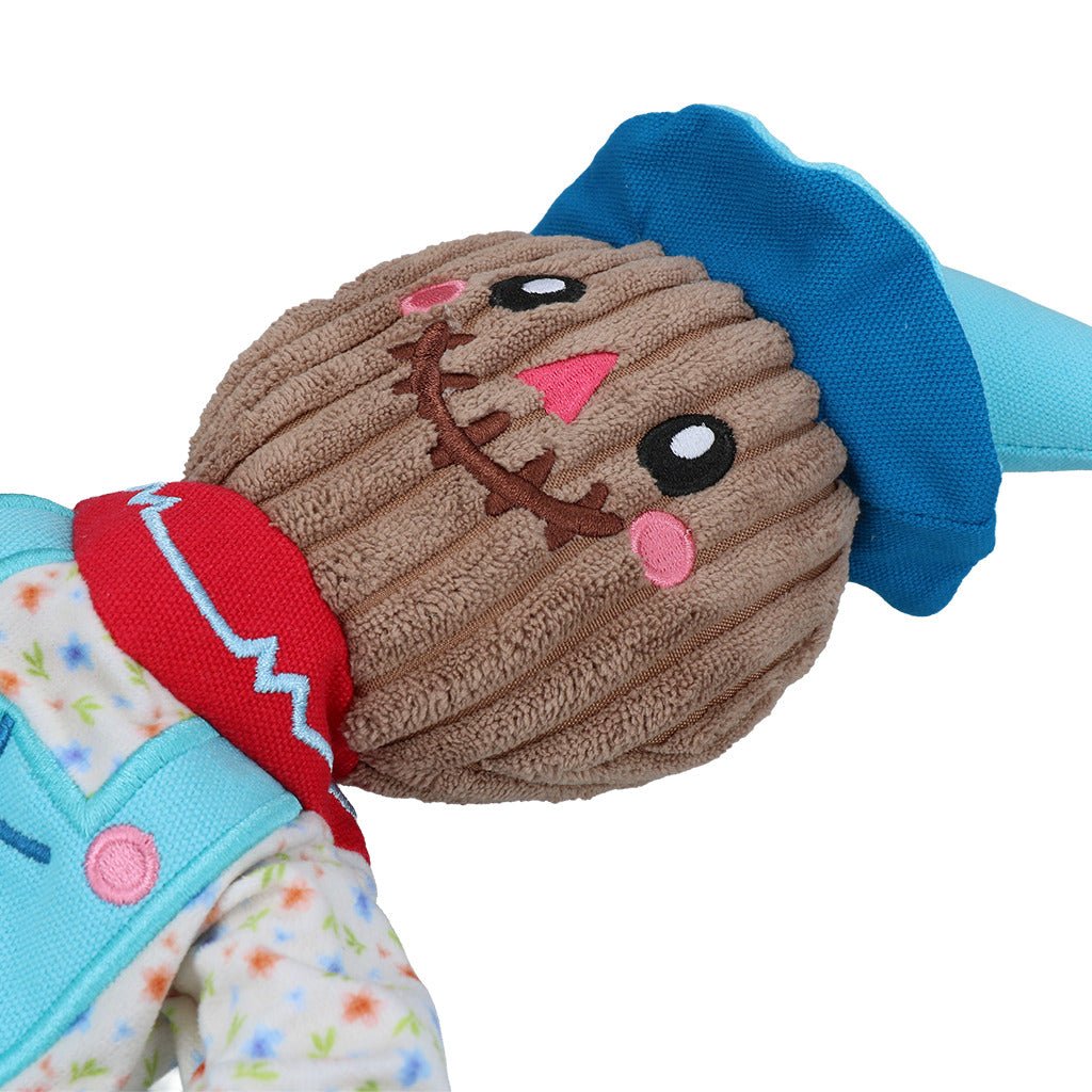 Plush toy with a brown face, blue ears, and colorful outfit on a white background