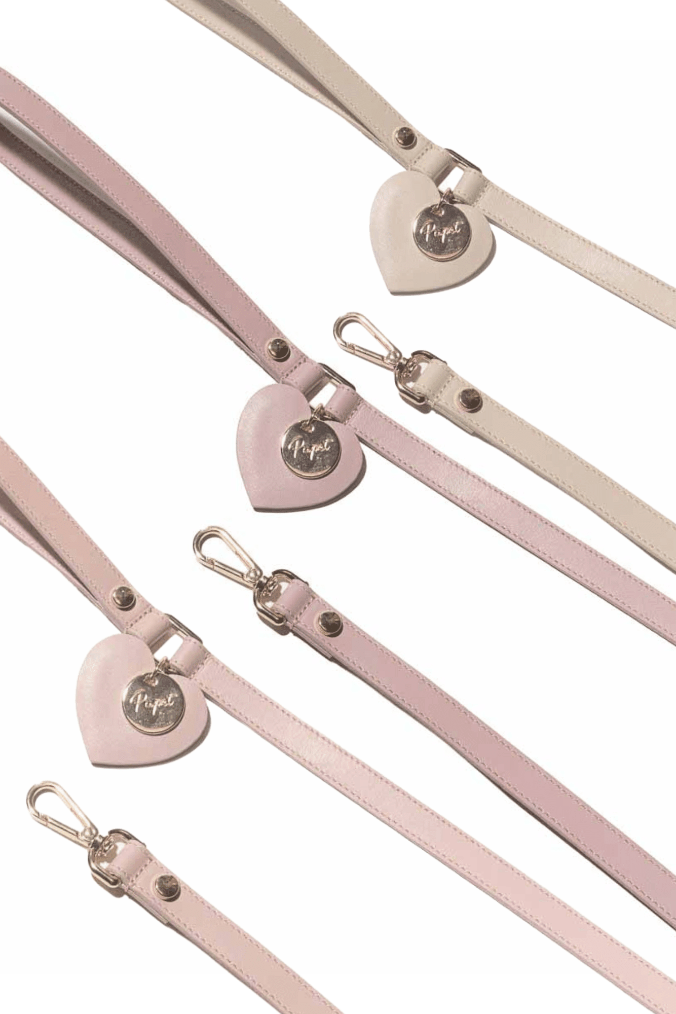 Pink leather straps with heart-shaped metal buckles on a white background