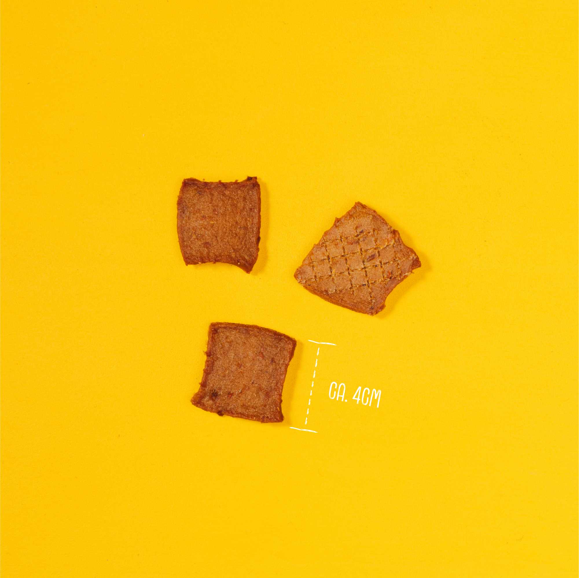 Three pieces of brown food on a yellow background with &