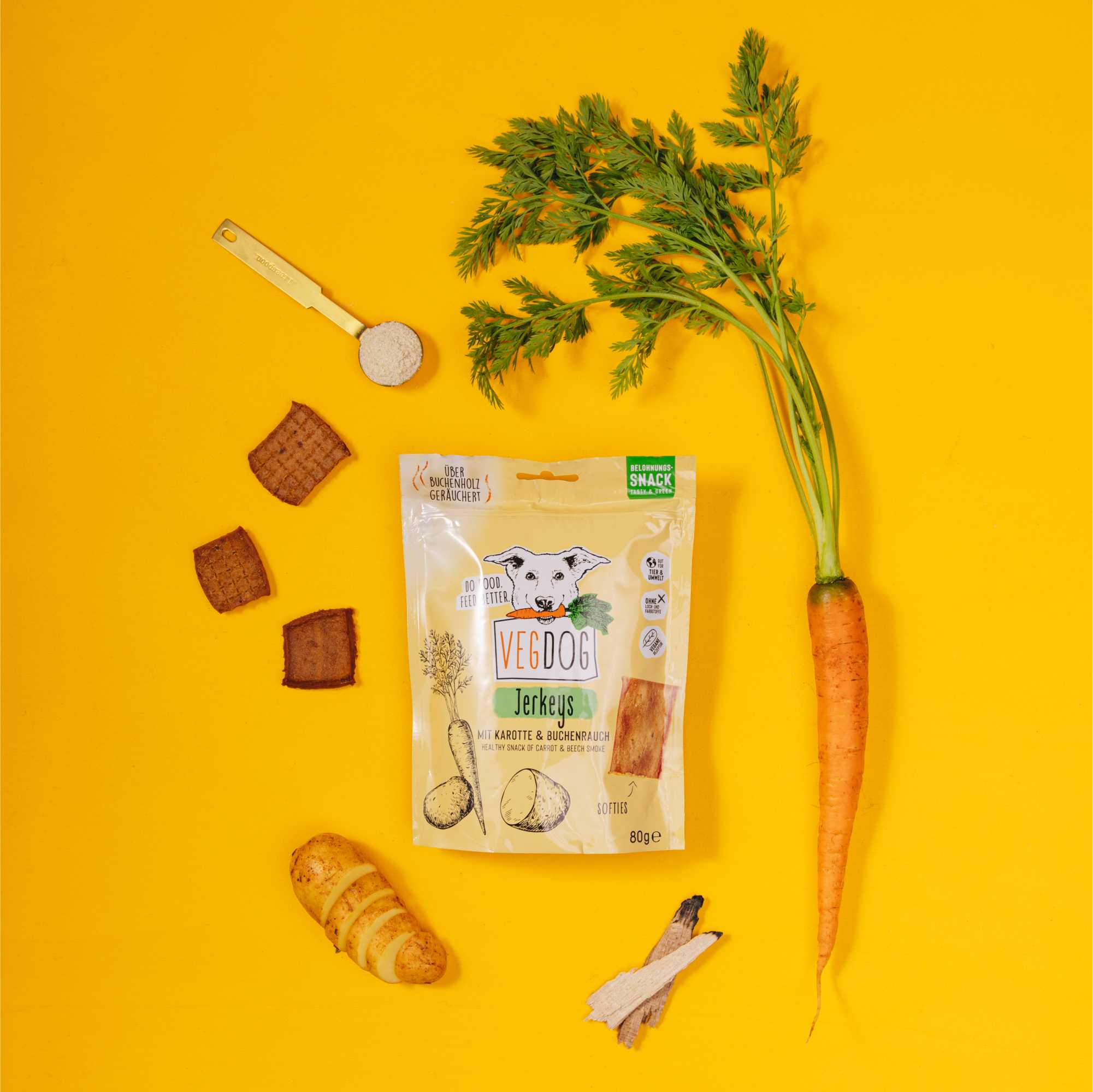 Veggie dog jerky package with a carrot and other treats on a yellow background