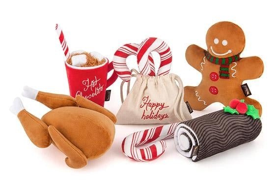 Collection of Christmas-themed plush toys including a gingerbread man, hot chocolate mug, candy cane, and cookies on a white background.