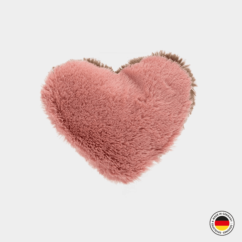 Heart-shaped pink fluffy pillow on a light gray background with a brand logo in the corner.
