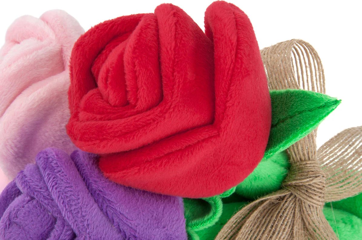 Close-up of a red felt rose with green leaves and gold accents on a white background