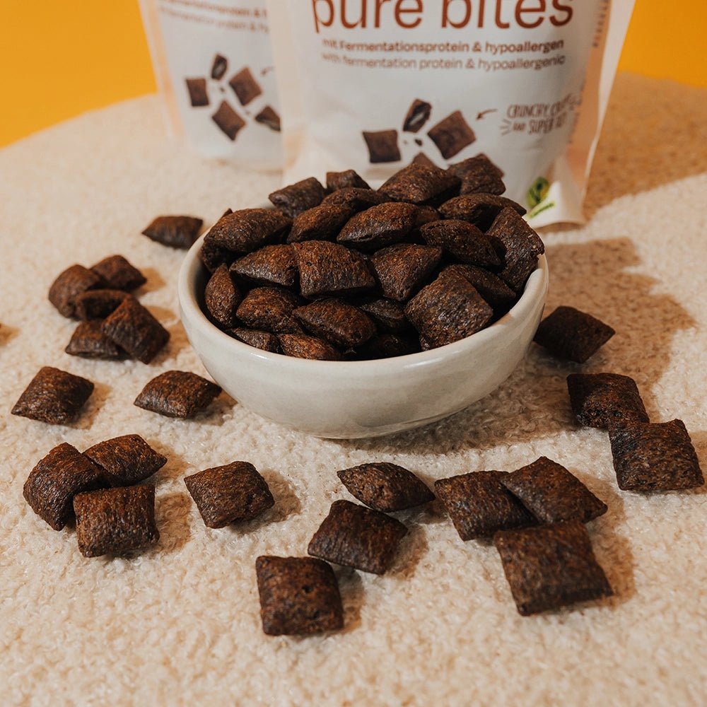 Bowl of brown protein bites with a container labeled &