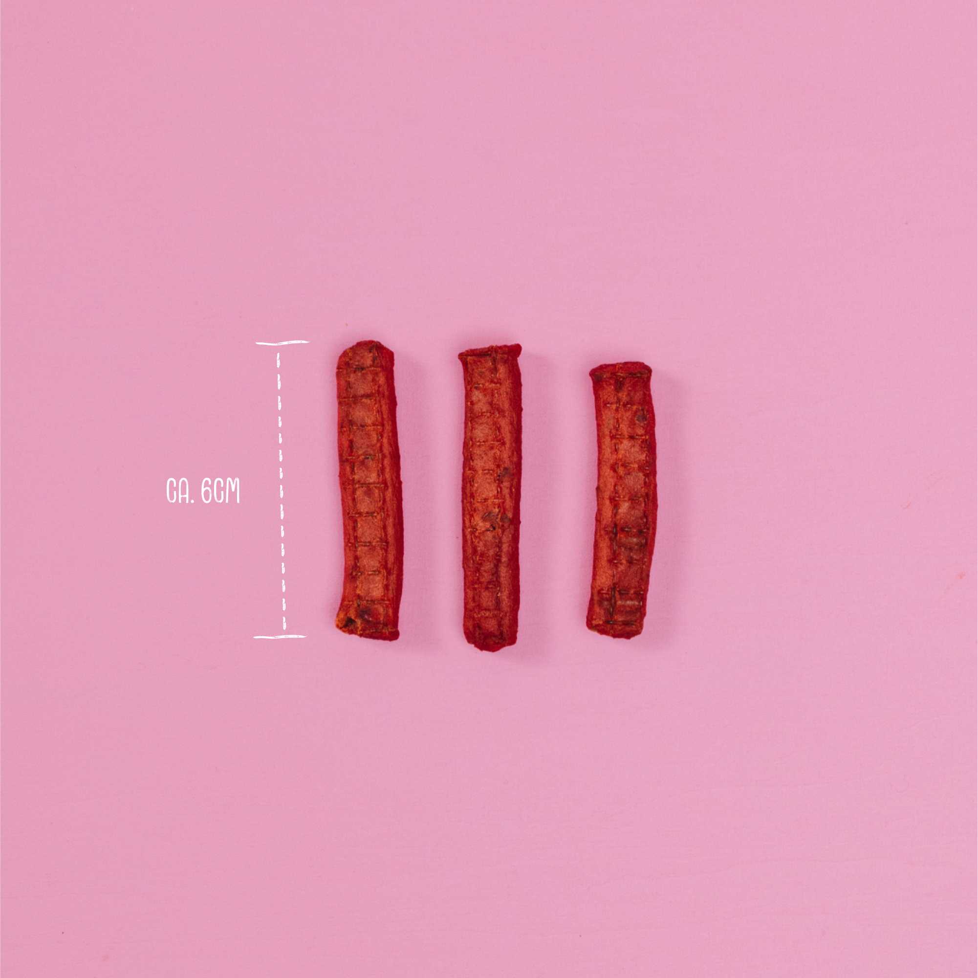 Three red dog treats on a pink background with measurement details.