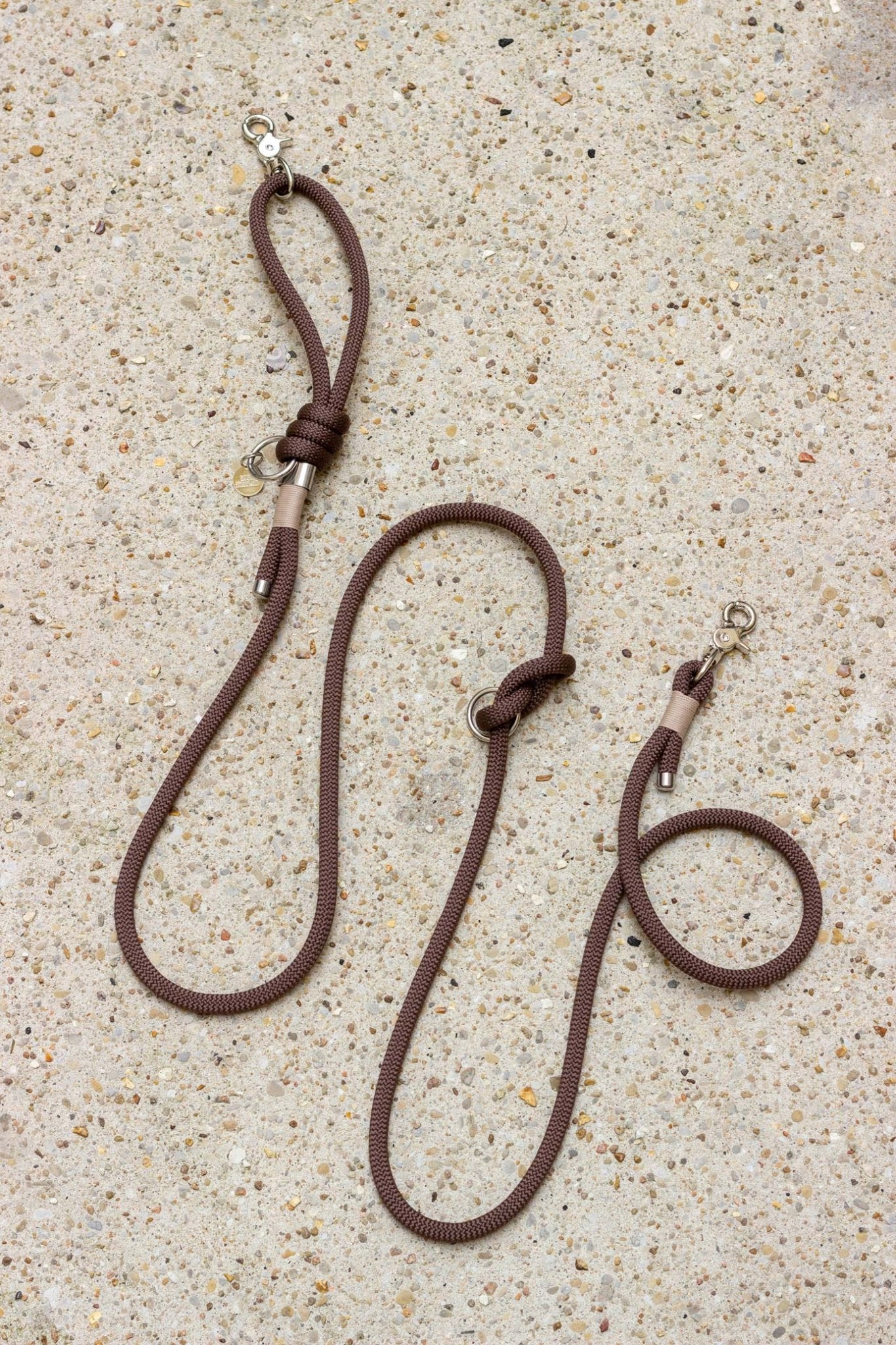 Two brown leather dog leashes on a textured surface