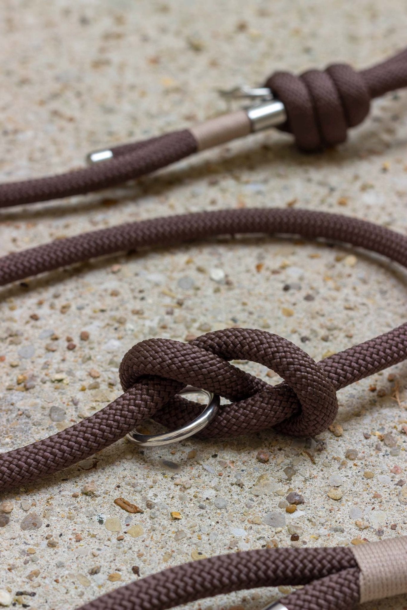 Close-up of brown rope with metal clasps on a textured surface
