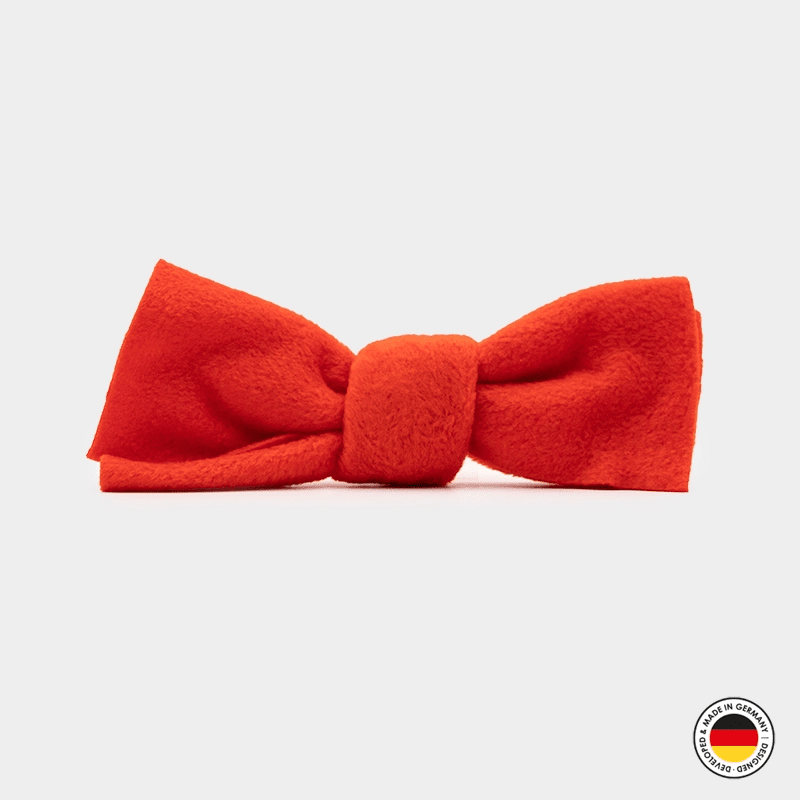 Red bow tie on a white background with a brand logo in the corner.