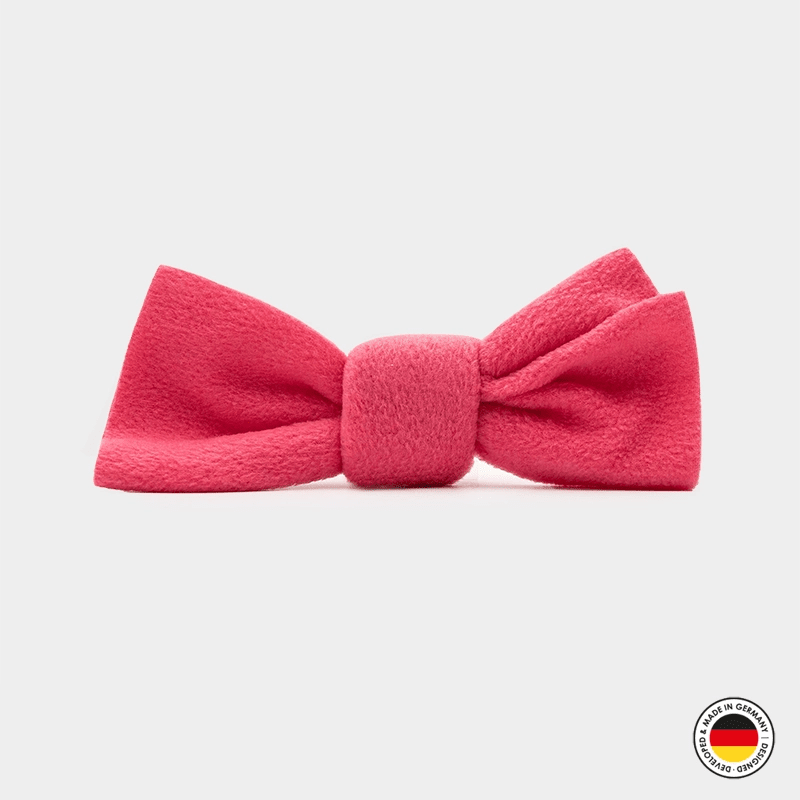 Pink bow tie on a light gray background with a brand logo in the corner.