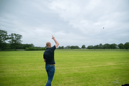 Man throwing a frisbee in a grassy field on a cloudy day