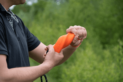 Person holding an orange object with a blurred green background