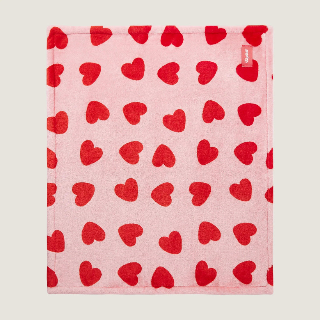 Pink towel with red heart pattern on a light pink background