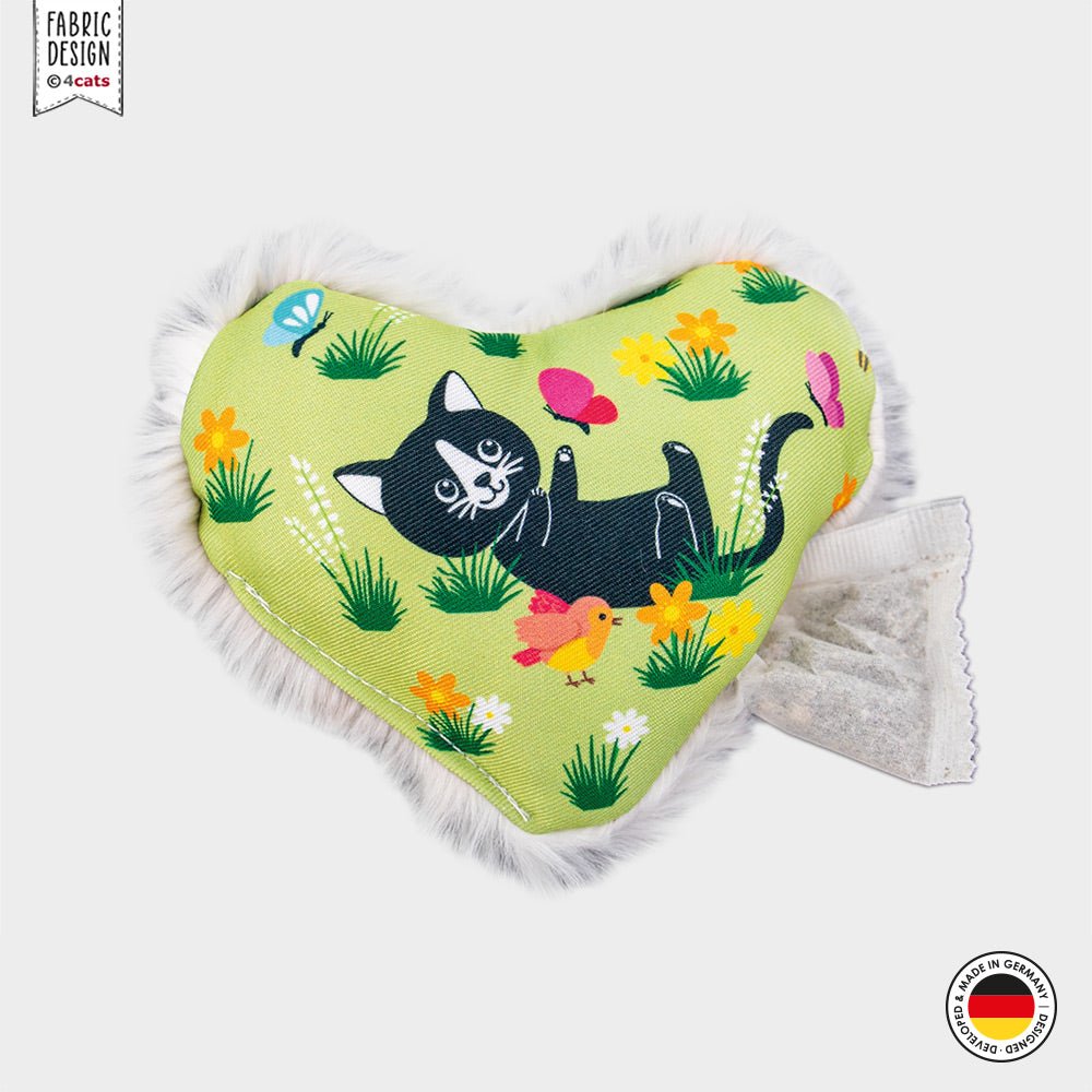 Heart-shaped catnip toy with a black cat design on a green background, featuring flowers and birds.