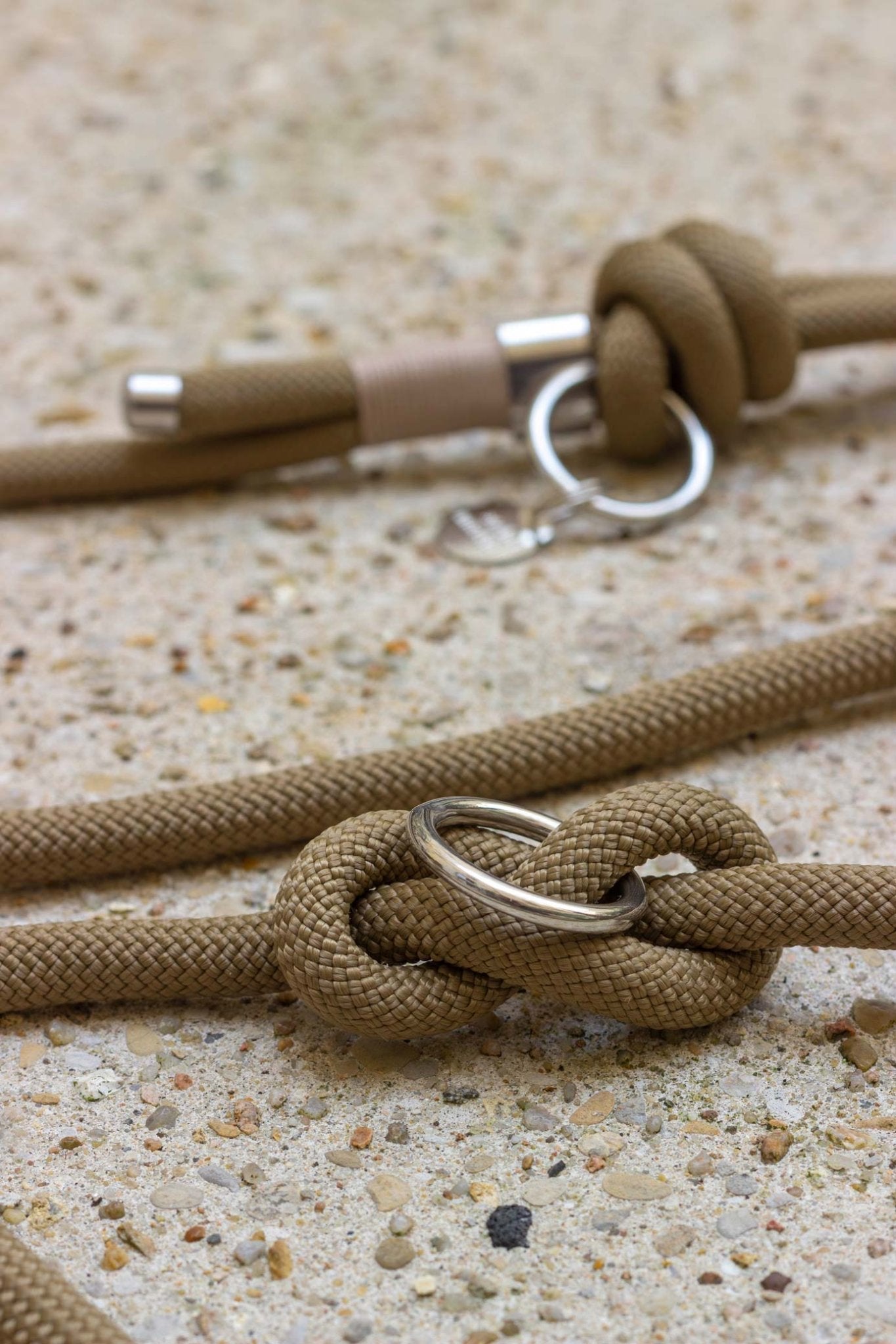 Close-up of a brown rope with metal rings on a textured surface