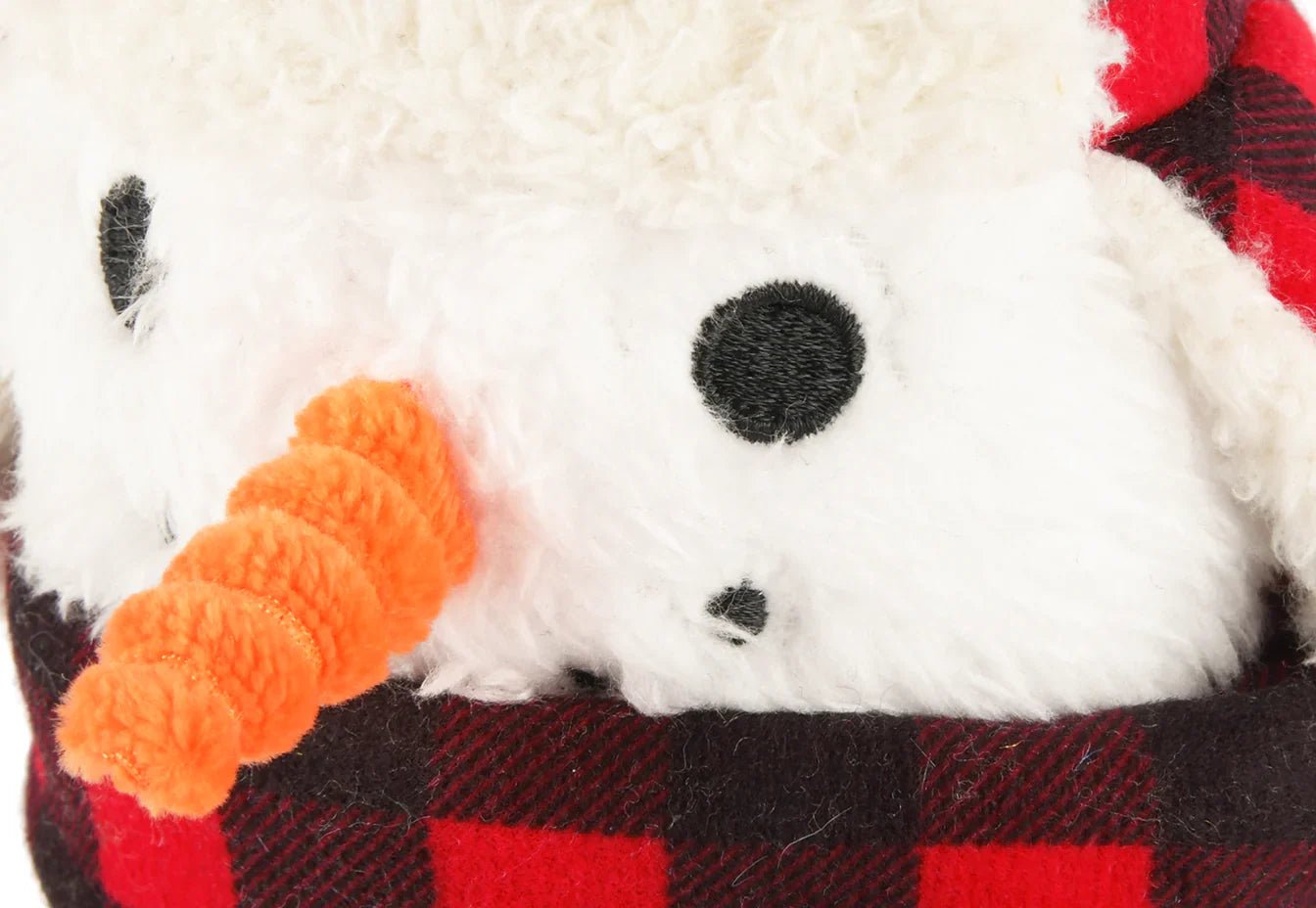 Close-up of a plush toy resembling a snowman with a red and black checkered scarf.
