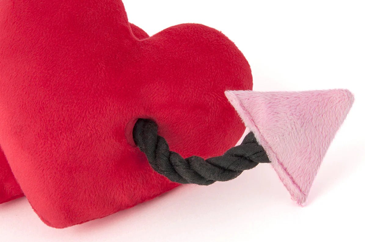 Red heart-shaped pillow with a black rope handle and pink triangle on a white background